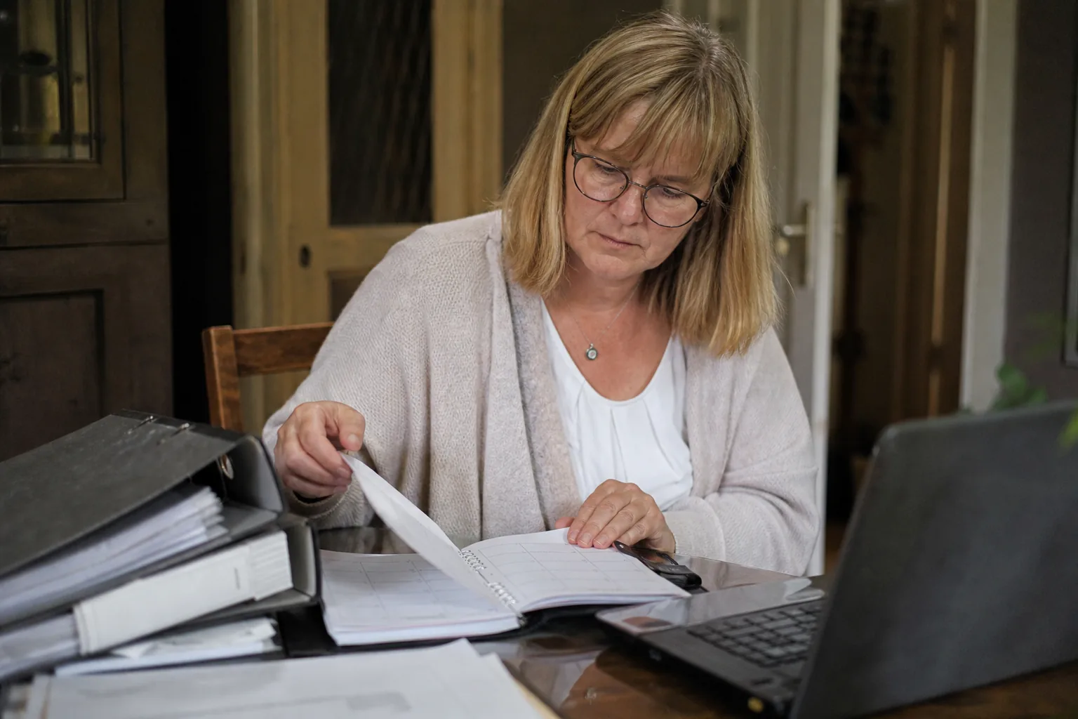 Vermieterin plant Termine für eine Betriebskostenabrechnung mit Kalender, Unterlagen und Laptop.